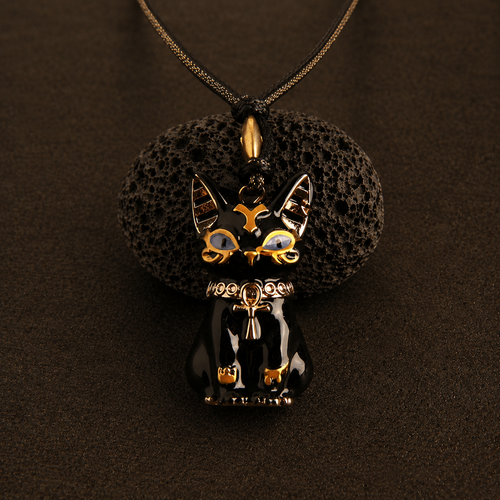 Black cat-shaped pendant with gold accents on a dark brown background