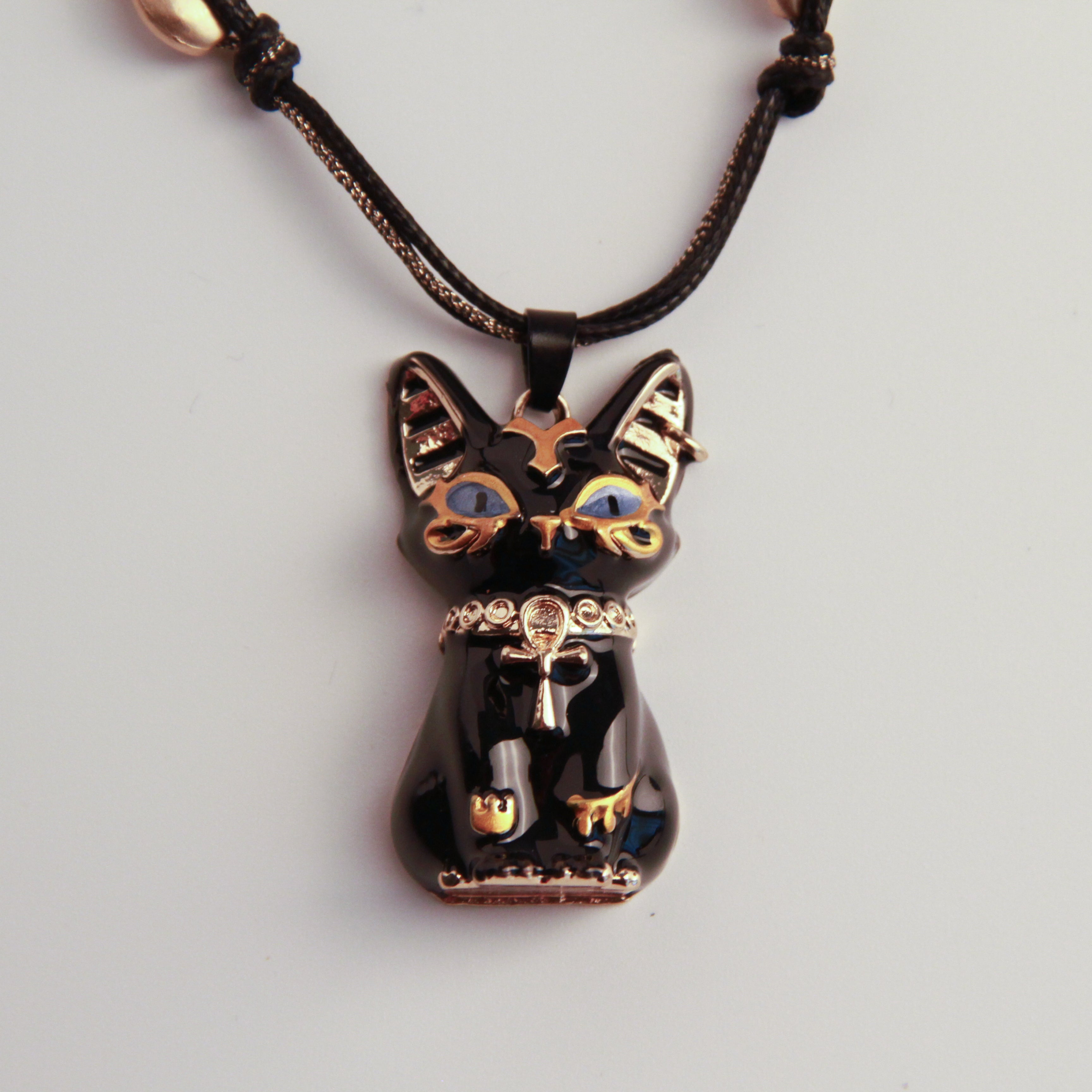 Cat-shaped pendant on a black cord against a light gray background