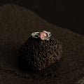 Silver ring with a red stone on a textured black surface