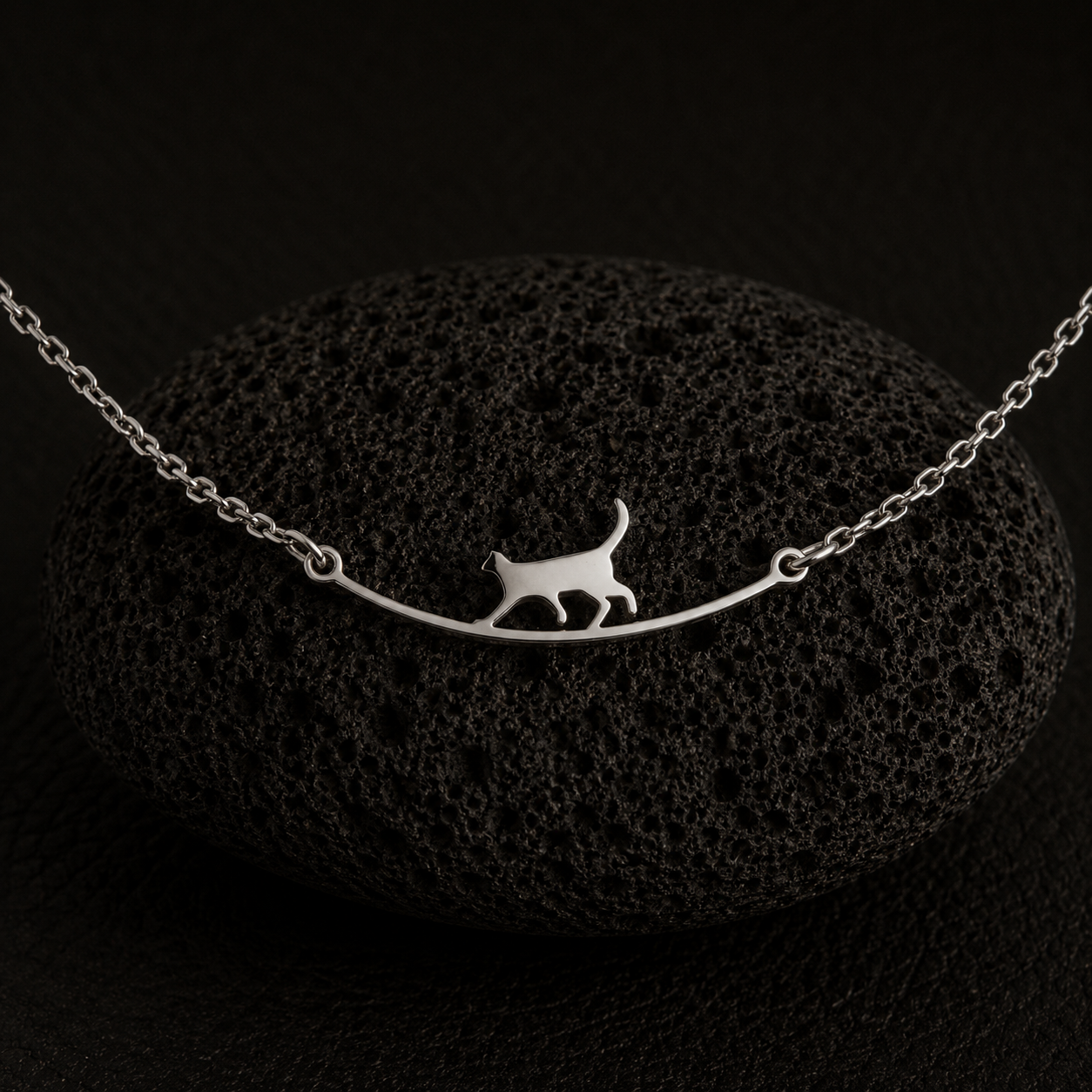 Side angle of the Curious Cat Bracelet resting on a black lava stone.