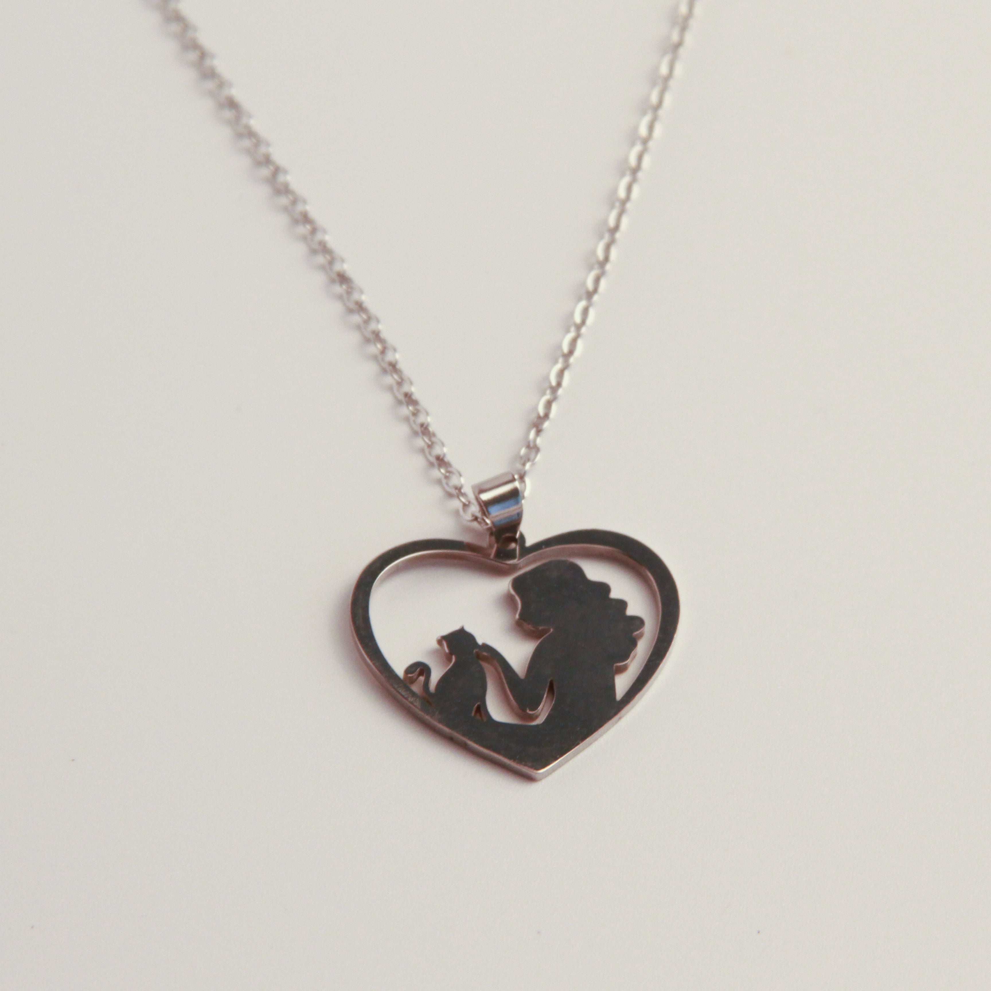Heart-shaped silver cat necklace with cat silhouette design, meaningful jewelry inspired by the bond between cats and their owners
