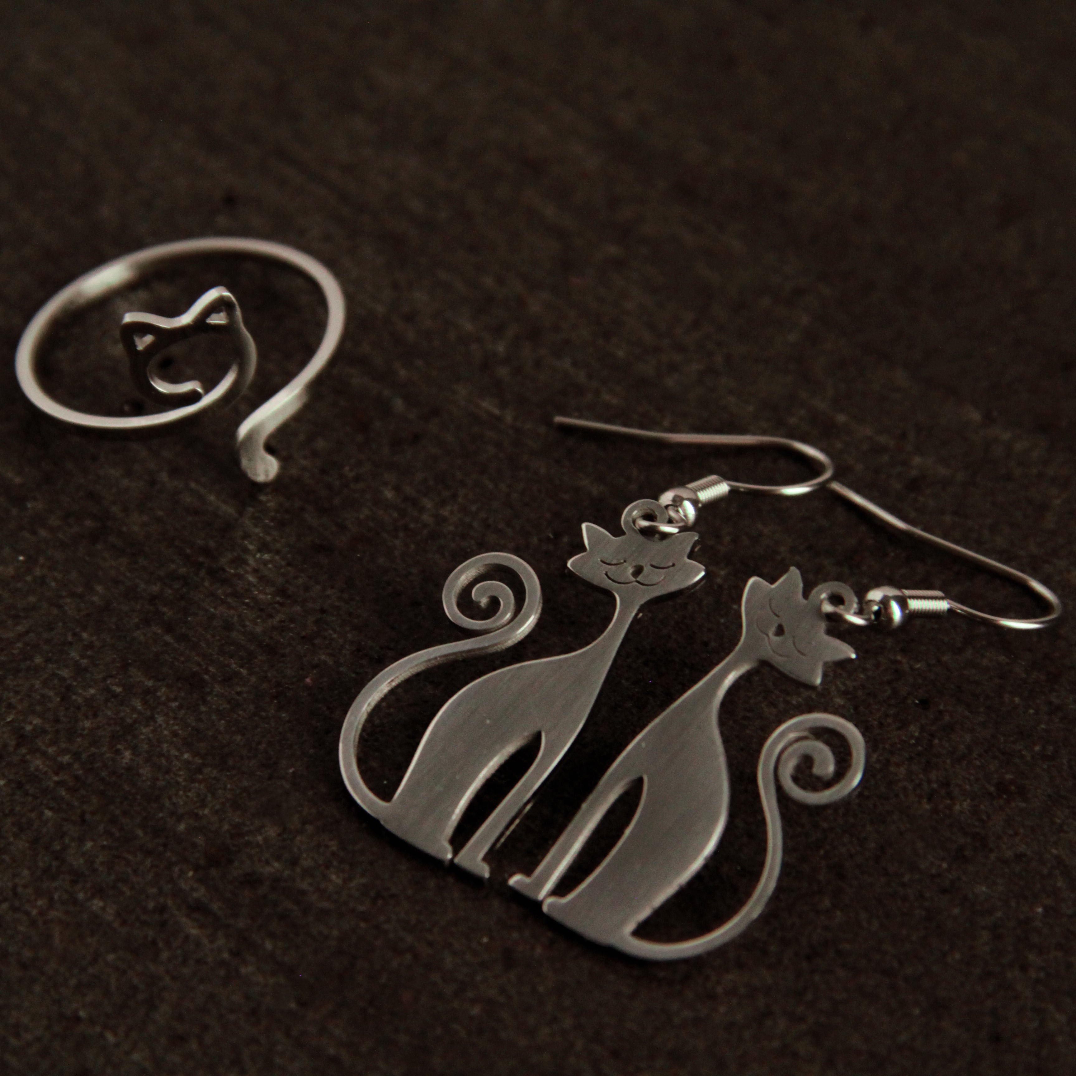 Silver cat jewelry set featuring dangling earrings and adjustable cat ring, stylish accessory collection for women