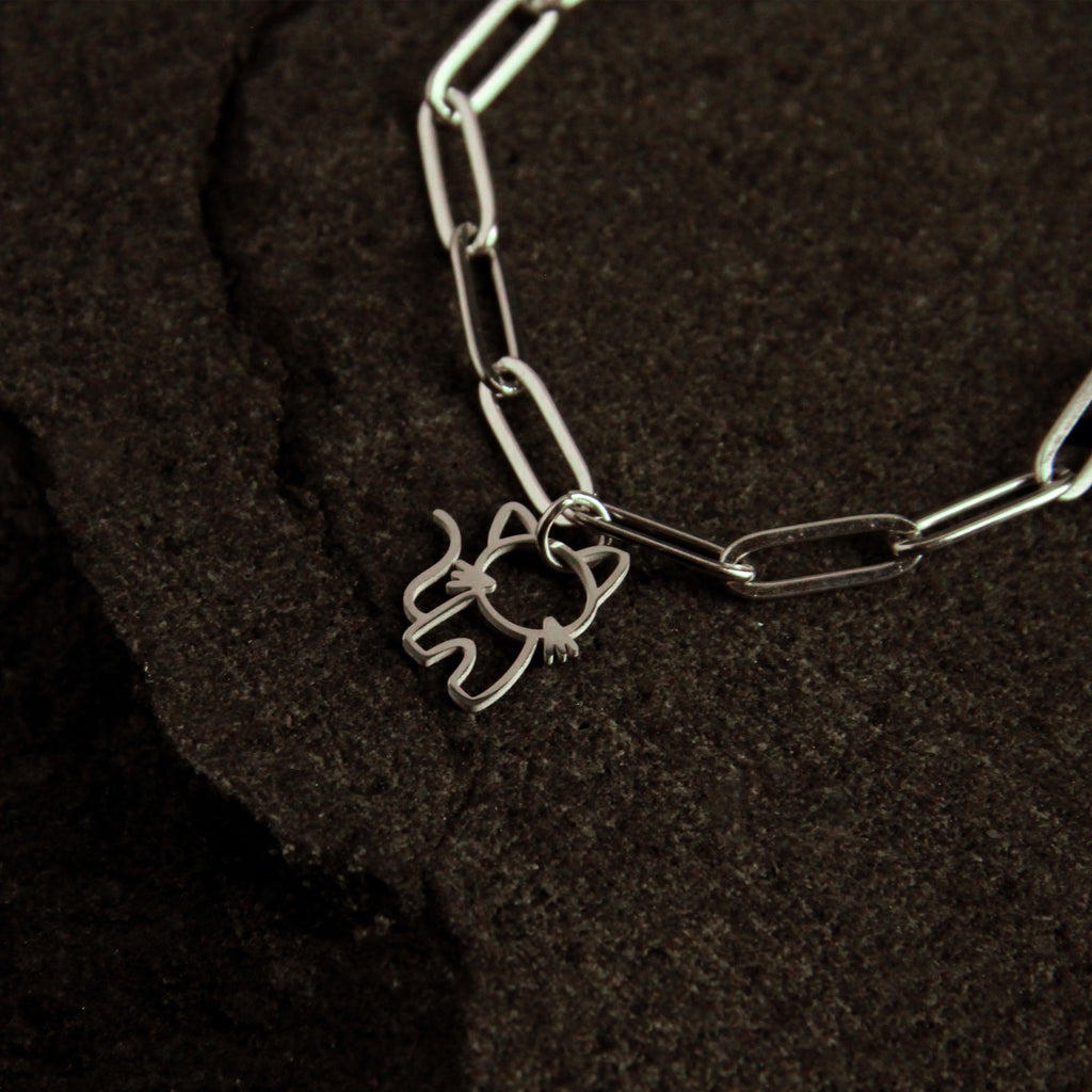 Silver bracelet with a cat-shaped charm on a dark textured surface