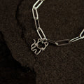 Silver bracelet with a cat-shaped charm on a dark textured surface