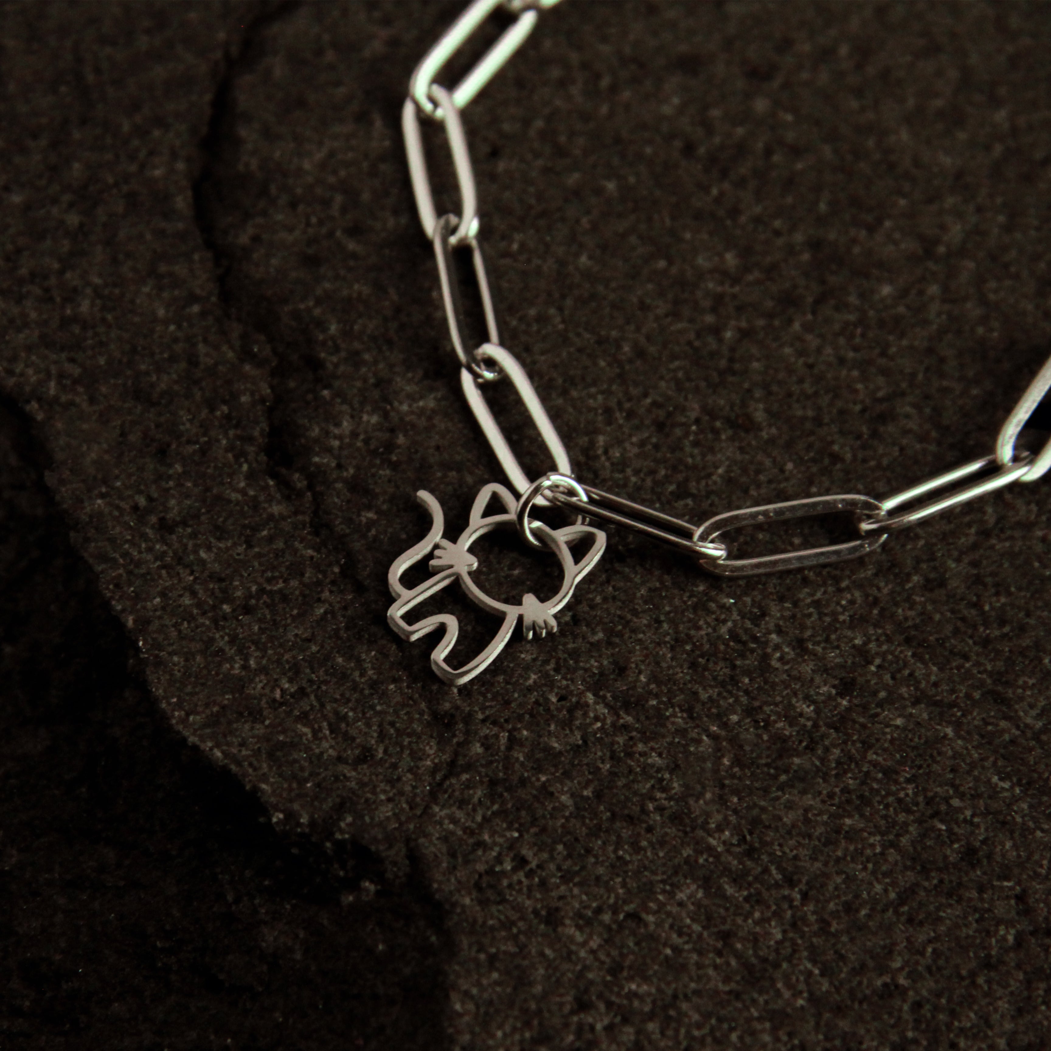 Silver bracelet with a cat-shaped charm on a dark textured surface