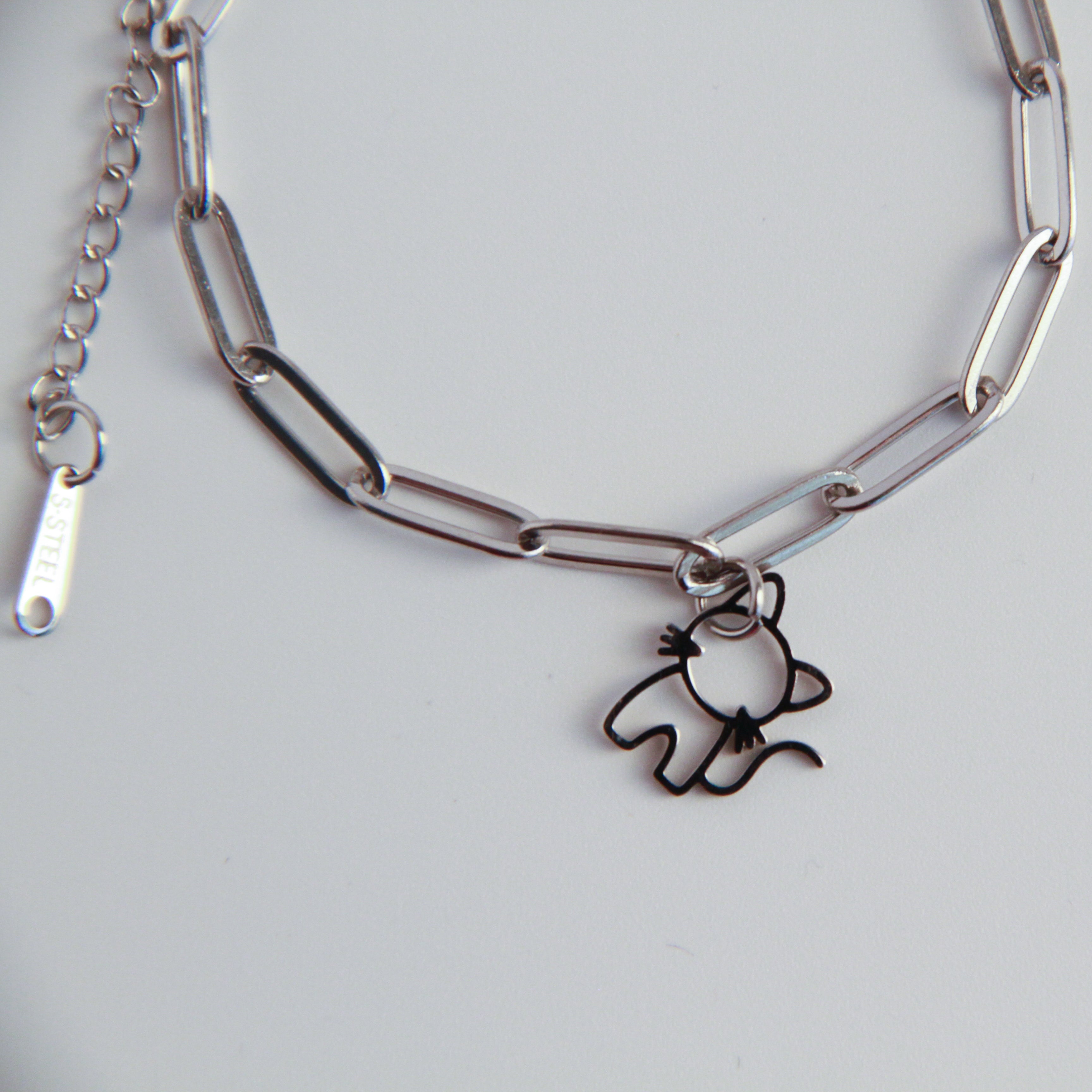 Silver chain bracelet with a cat-shaped charm on a light gray background