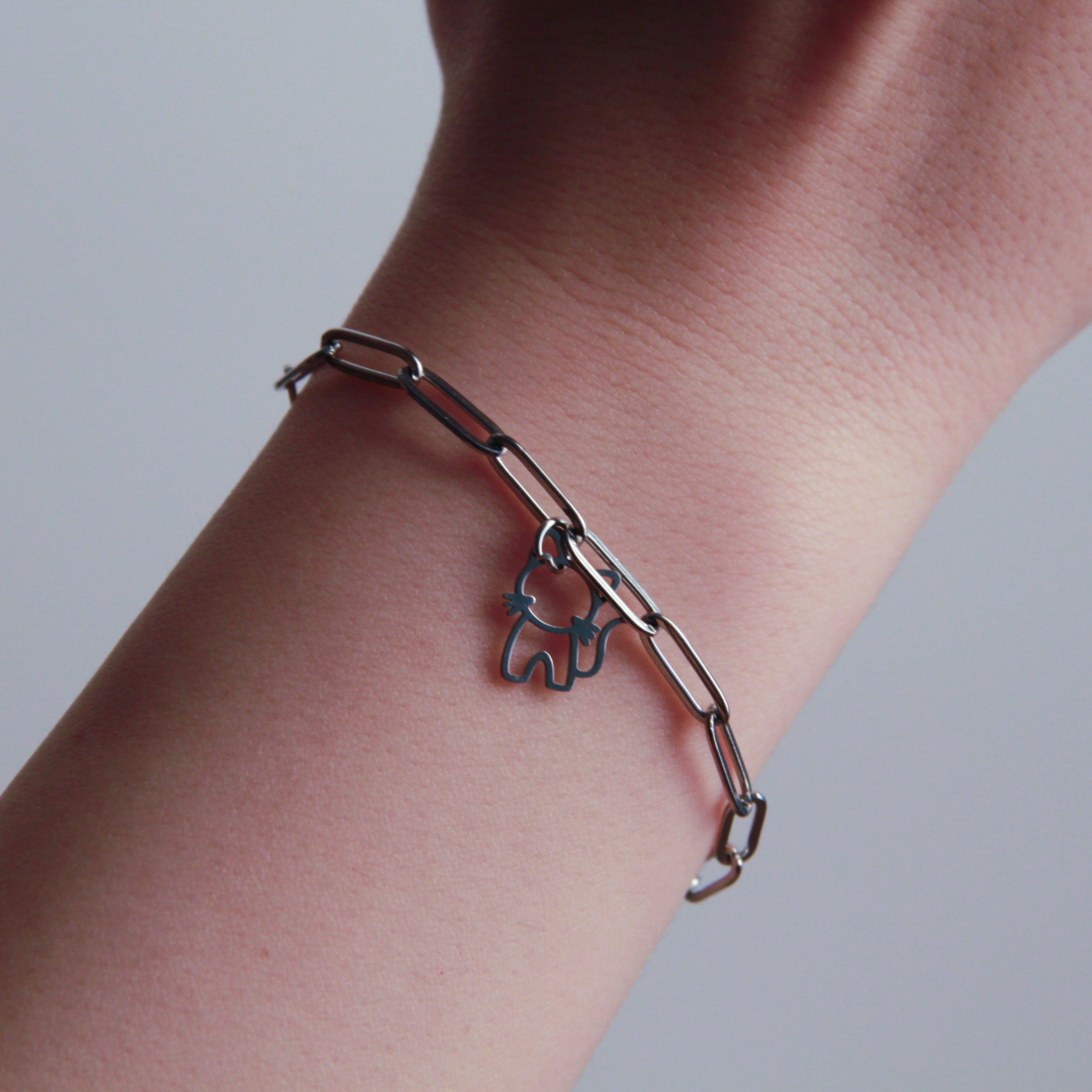 Silver chain bracelet with an elephant charm on a wrist against a neutral background
