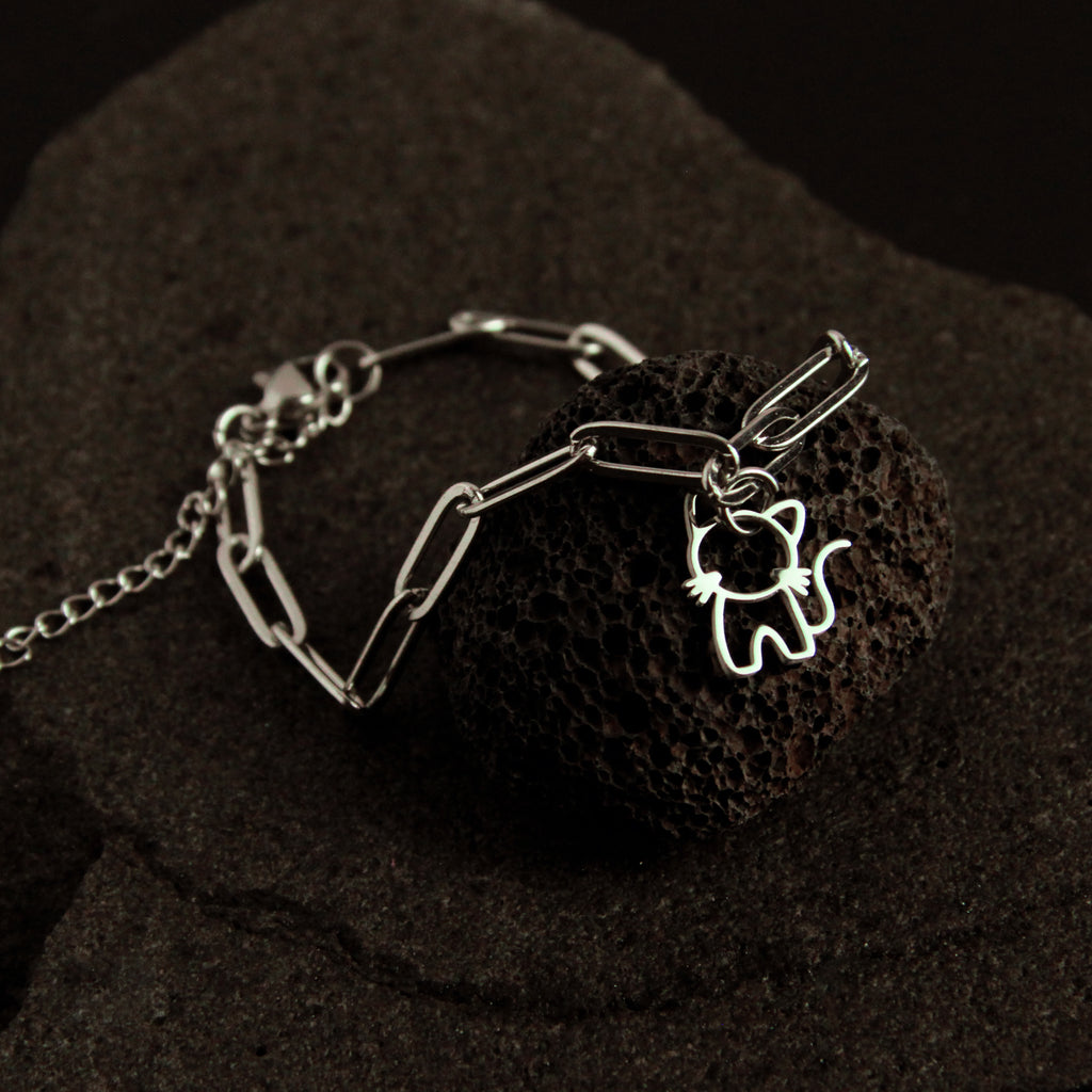 Silver bracelet with a cat-shaped charm on a dark textured surface