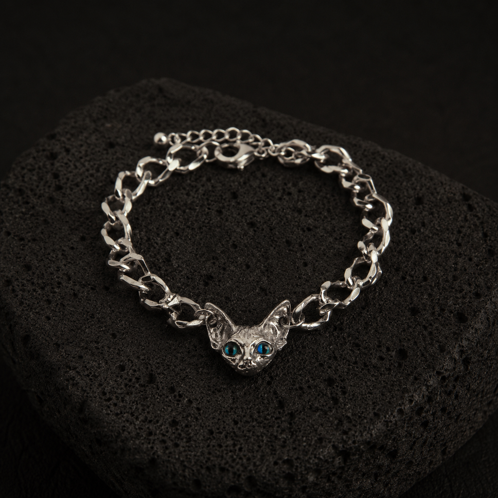Silver-plated Sphynx Guardian Bracelet with a blue-eyed sphynx cat charm displayed on a black lava stone.