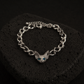 Silver-plated Sphynx Guardian Bracelet with a blue-eyed sphynx cat charm displayed on a black lava stone.