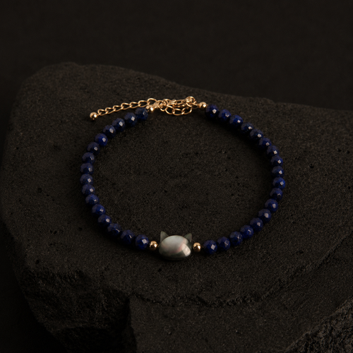 Blue faceted bead bracelet with an iridescent cat charm and gold accents.