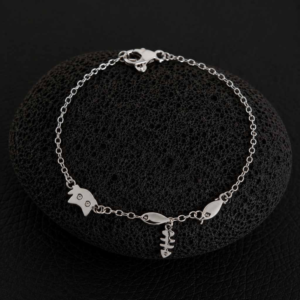 Silver cat charm bracelet with fishbone and fish charms on a delicate chain.