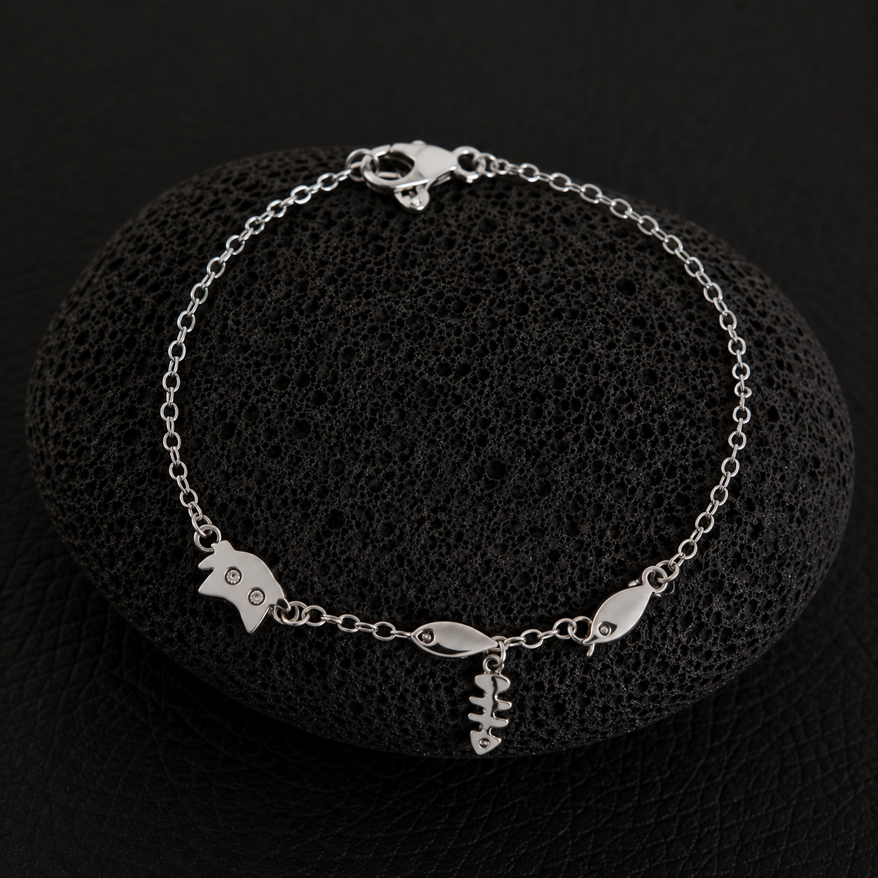 Silver cat charm bracelet with fishbone and fish charms on a delicate chain.