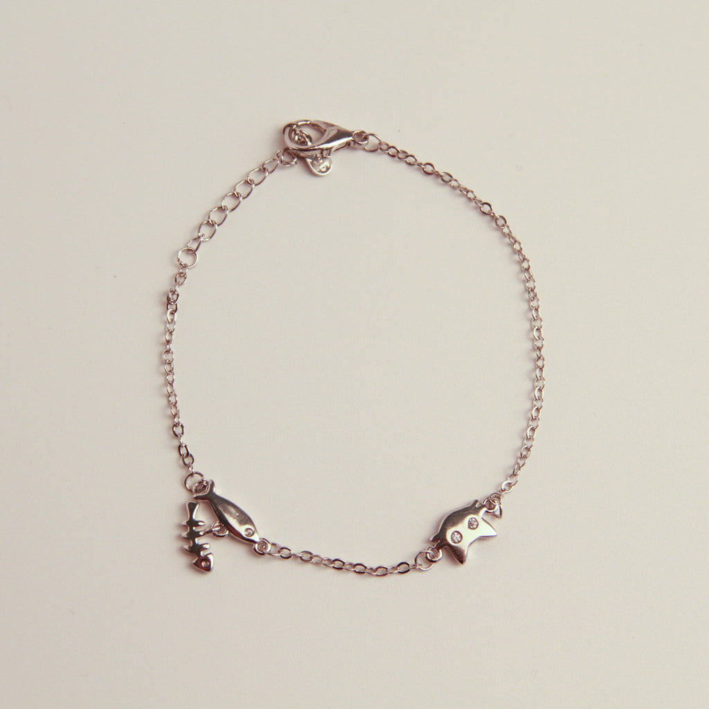 Silver cat charm bracelet with fishbone and fish charms on a delicate chain.