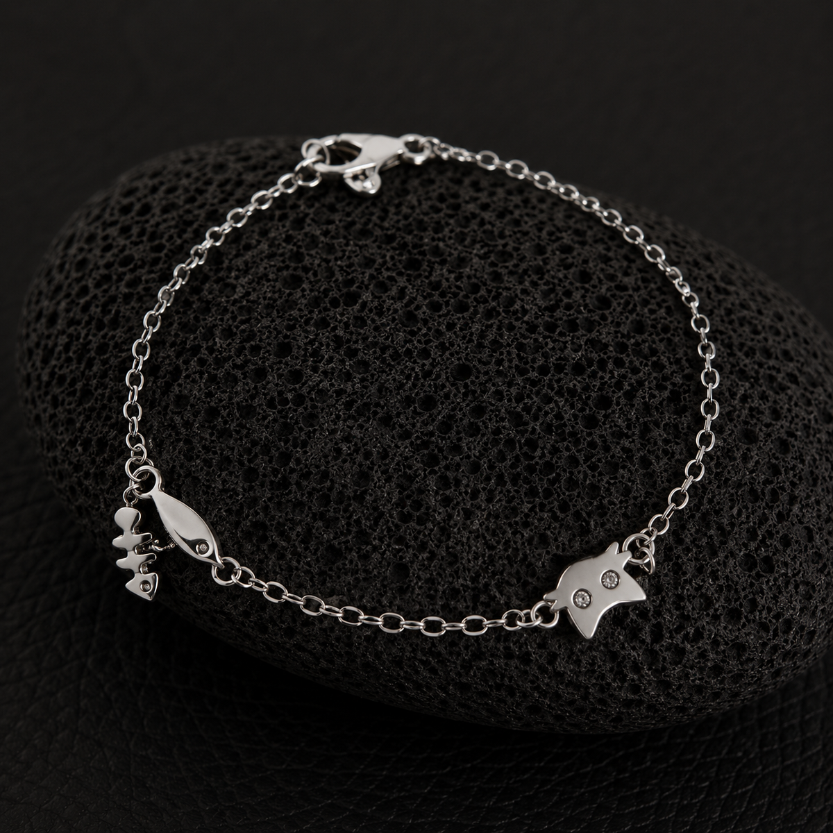 Silver cat charm bracelet with fishbone and fish charms on a delicate chain.