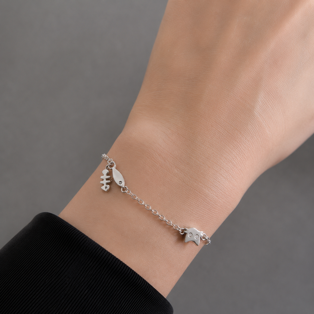 Silver cat charm bracelet with fishbone and fish charms on a delicate chain.