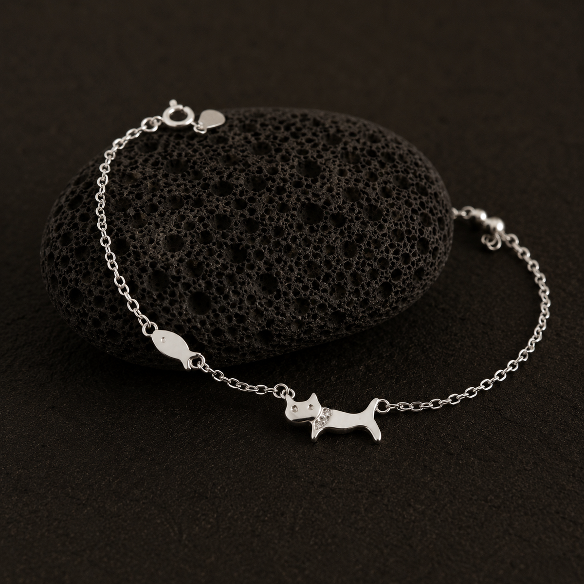 Silver bracelet with a cat charm on a black stone background